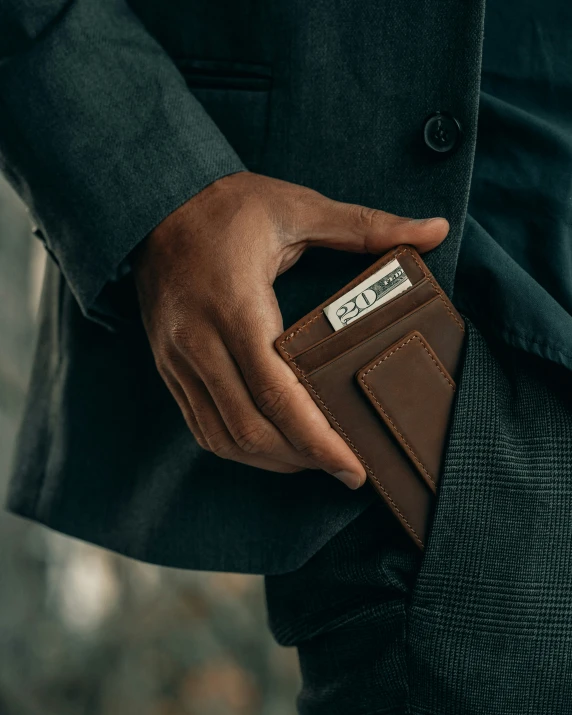 a man in a dark suit holds his wallet