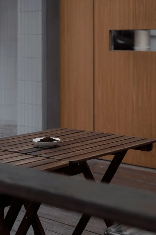 a wooden table and some silverware on a patio