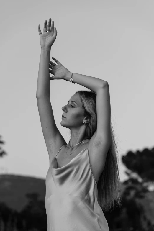 black and white pograph of a woman wearing a dress and holding her hands up