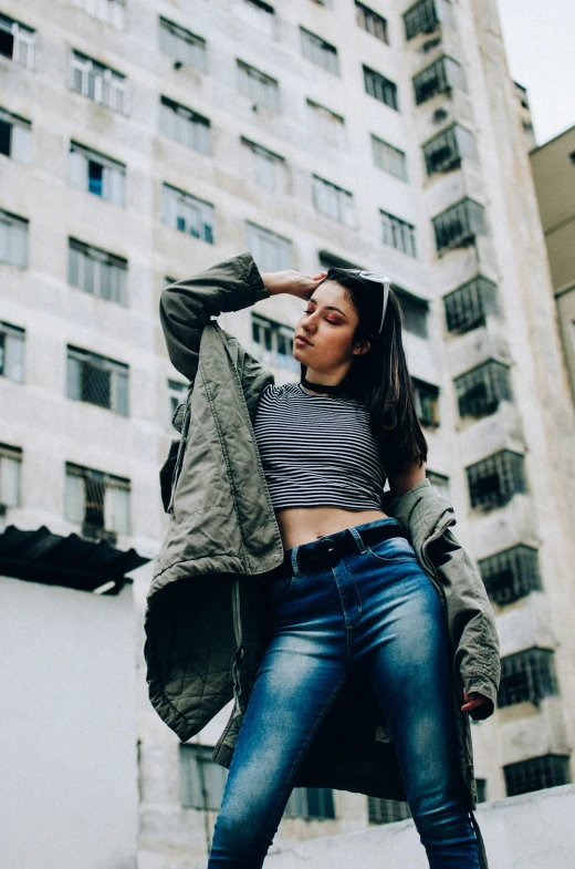 a woman wearing blue jeans, striped shirt and a coat on