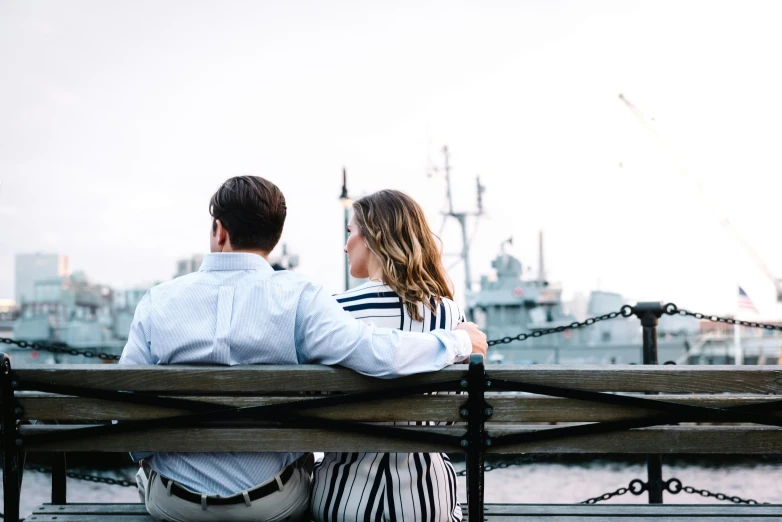 a couple sitting on a bench looking at the city