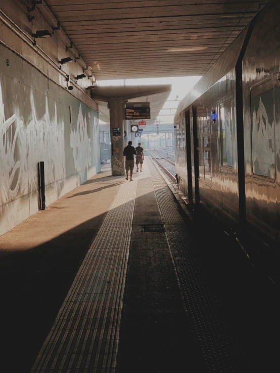 two people walk along side a subway train