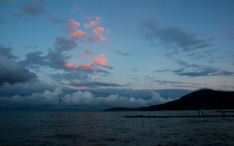 a blue ocean with a small group of clouds on the shore