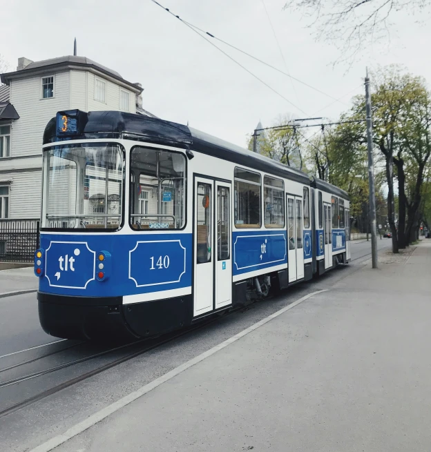 a blue and white train on its track next to a building