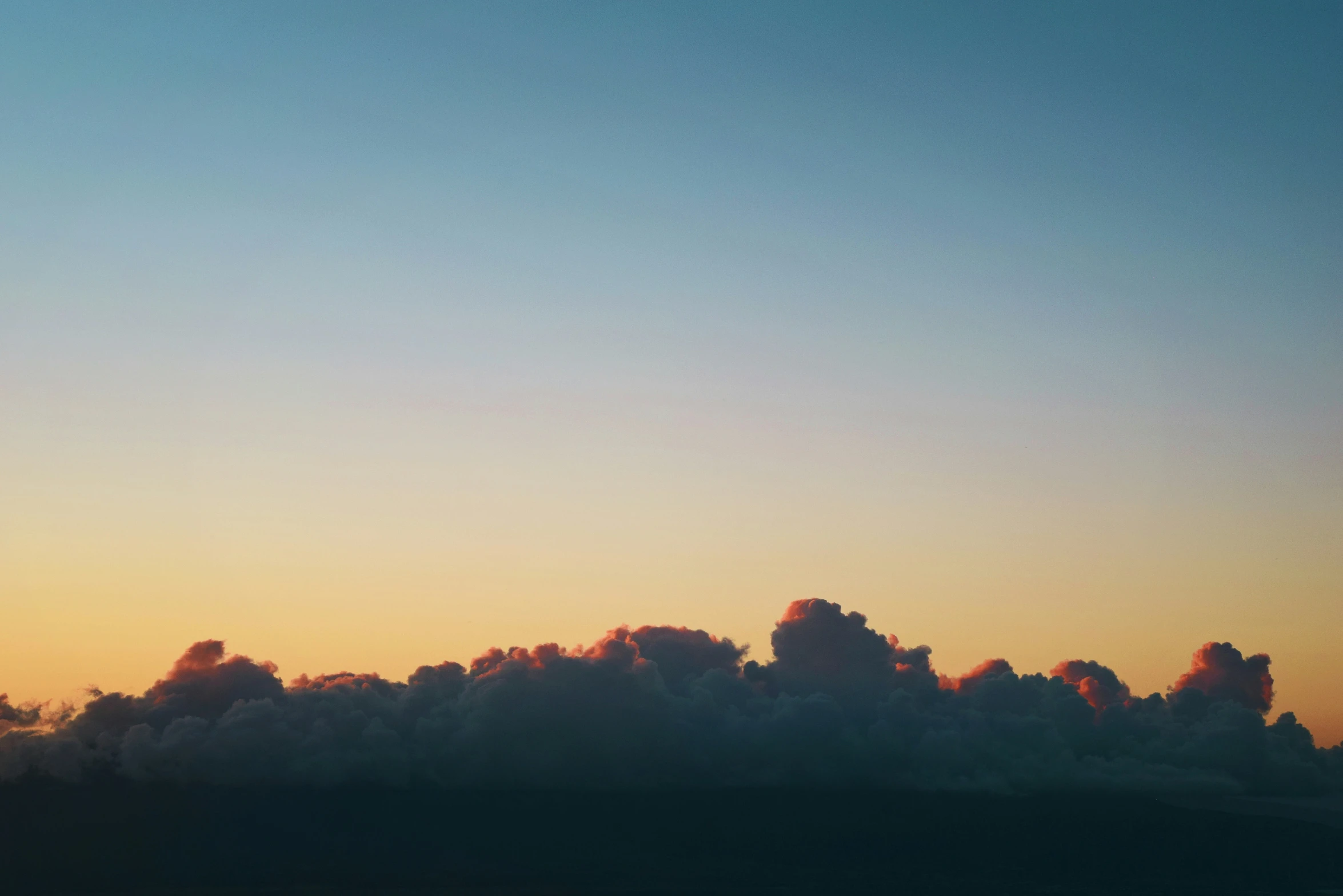 a plane flying across a cloud filled sky