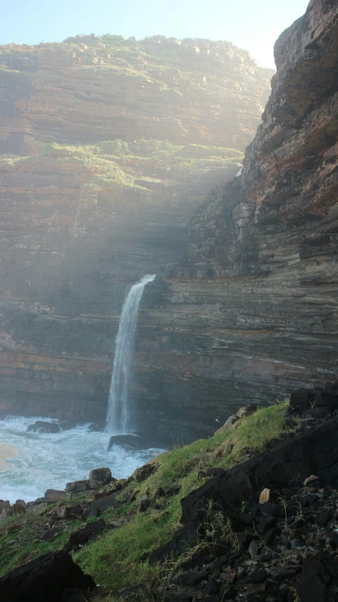 a tall waterfall towering over a lush green field