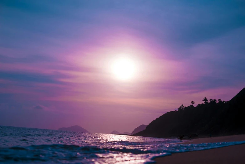 an ocean sunset with mountains and water