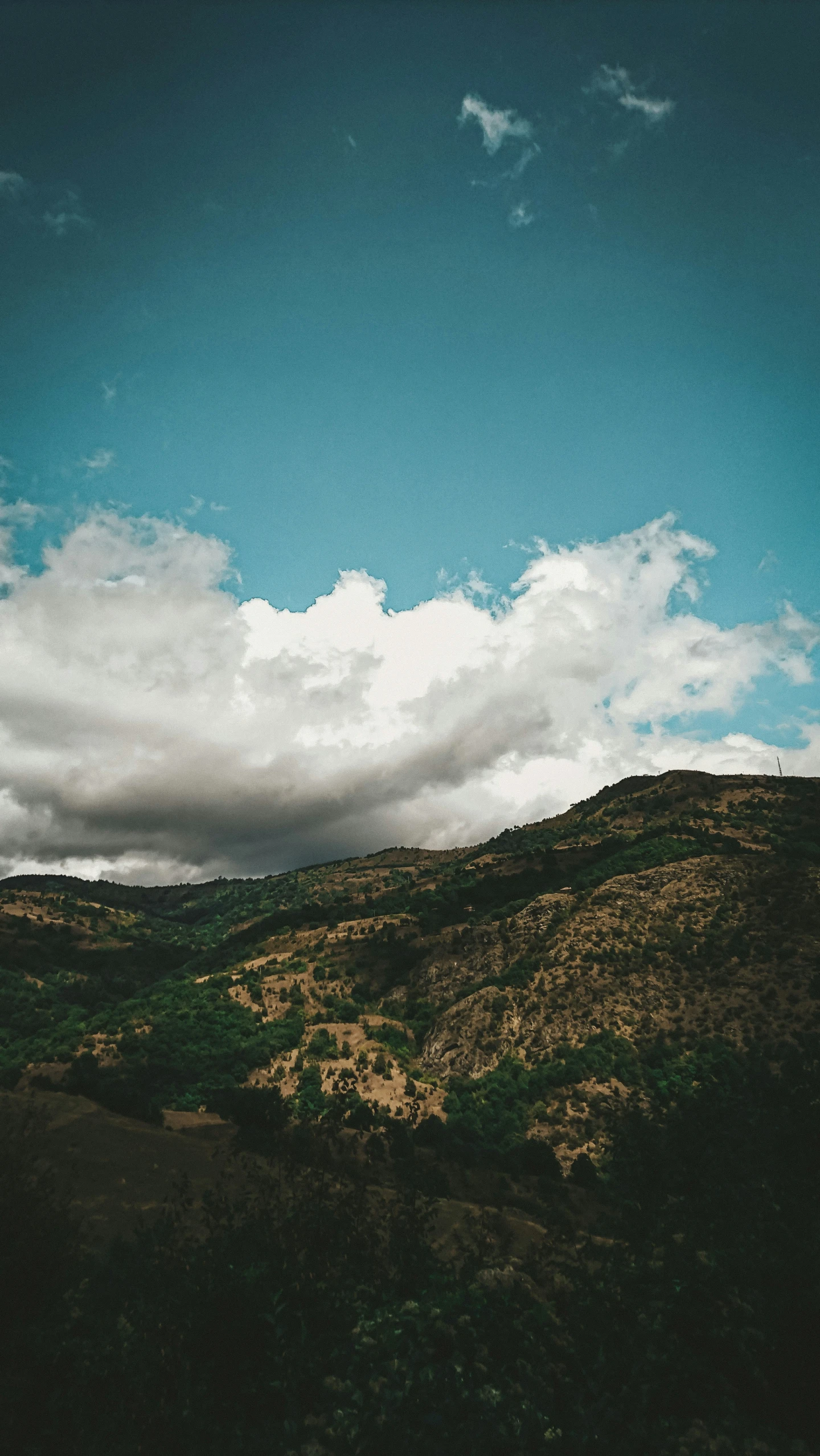 a view of a valley under a cloudy blue sky