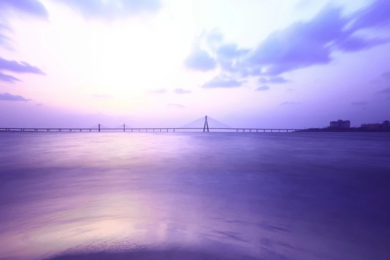 purple hued po of a bridge across the water