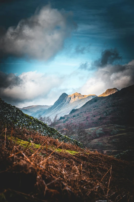 the mountains and grass in the distance under a blue cloudy sky