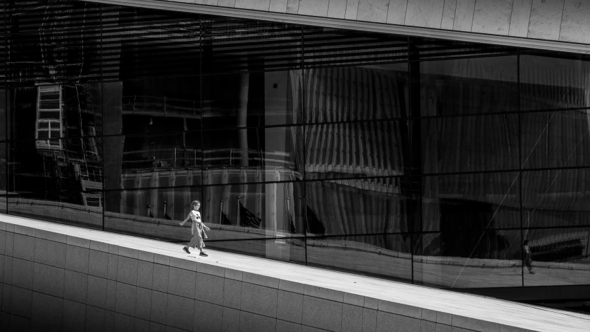 a person walking down a street past an office building with lots of glass