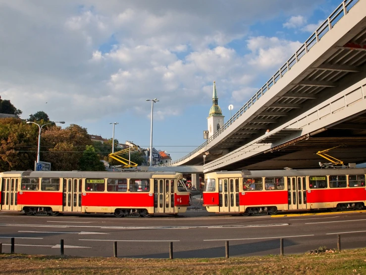 two trains pass each other in front of an overpass