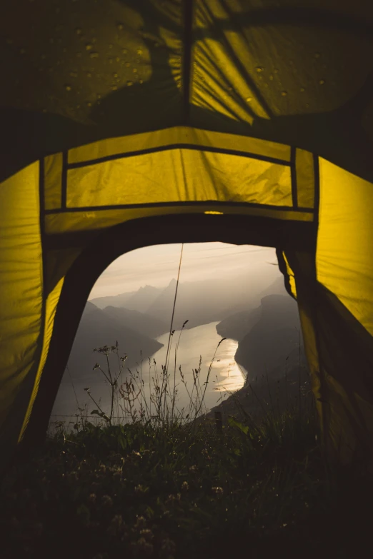 the view out of a tent is overlooking a body of water