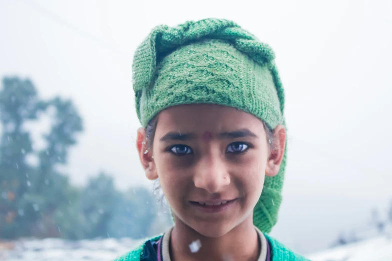 a little girl in green knitted hat outside