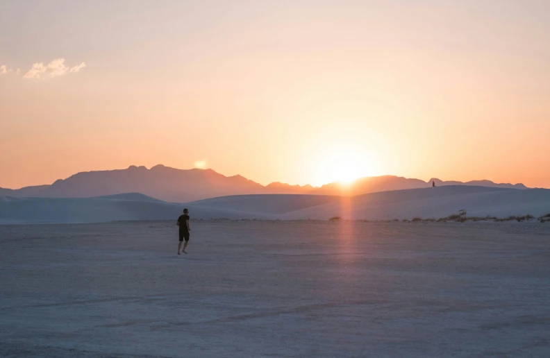 a woman standing in the desert at sunset