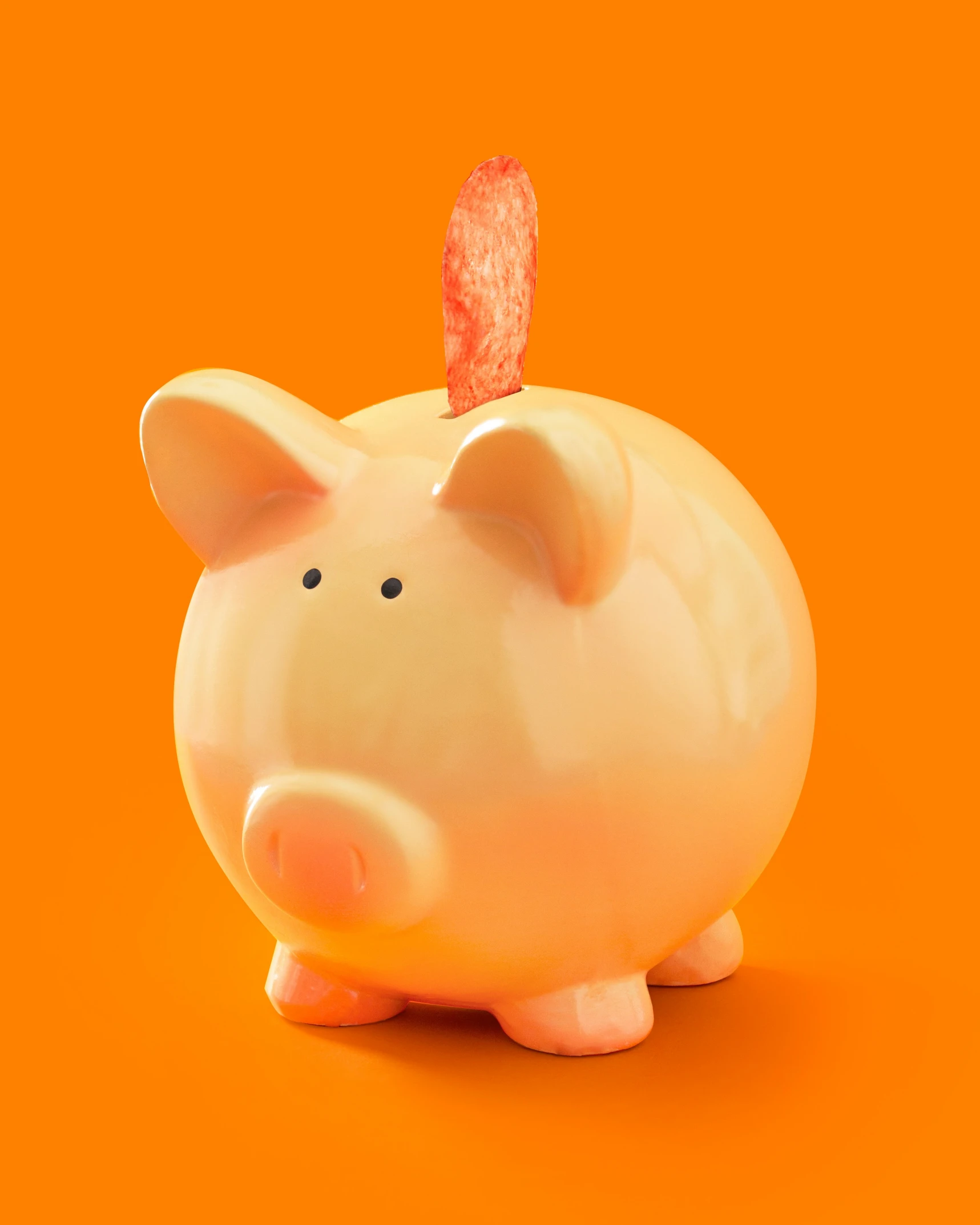 an orange piggy bank with a red cap on top