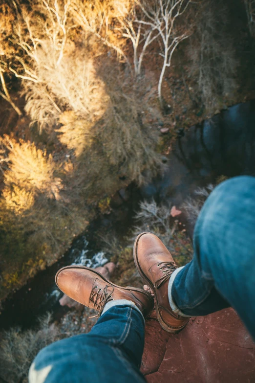 a person wearing brown shoes standing on top of a hill