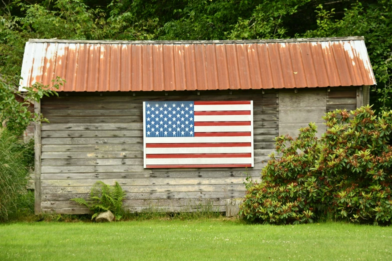 an american flag is hung on the side of a shed