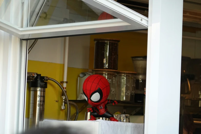 a spider - man statue with eyes is near a window