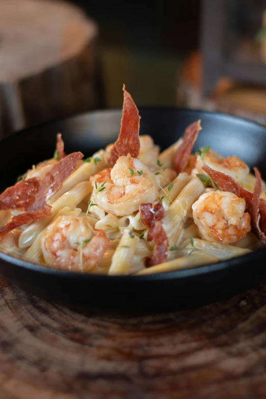 a plate of pasta with shrimp and ham on top