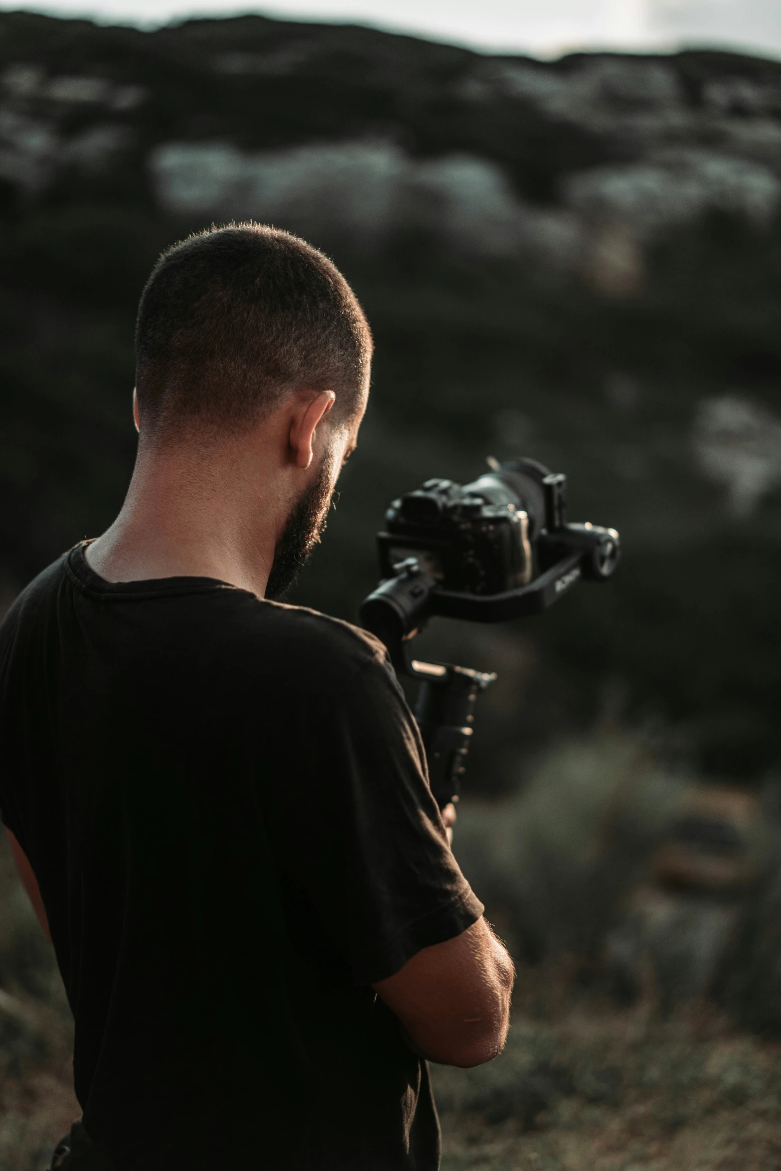 a man holding a camera standing in a desert