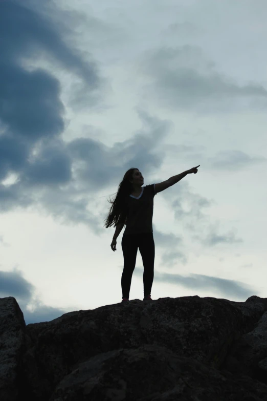 woman pointing with her hand standing on a rock