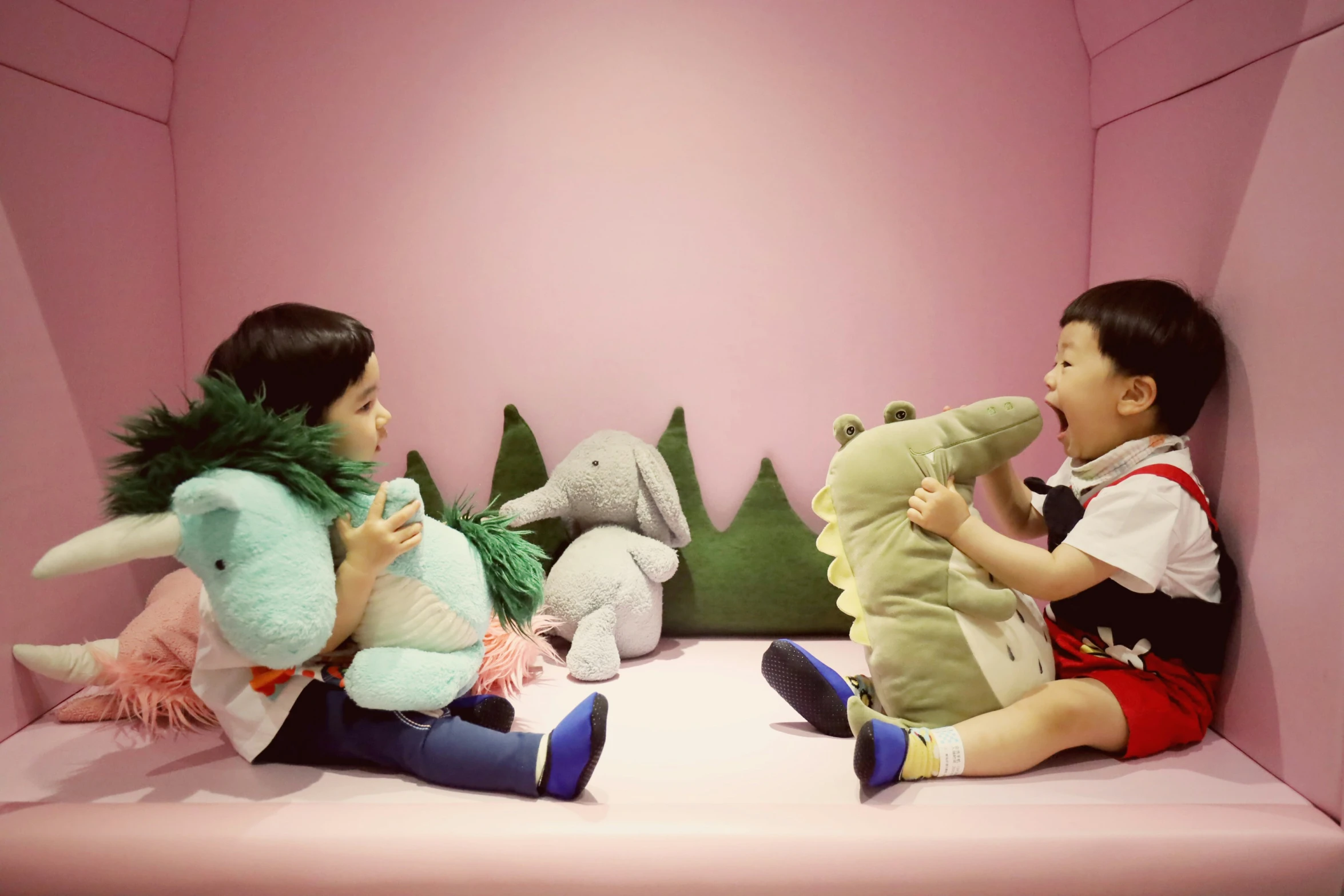 two young children sitting on pink benches with stuffed animals