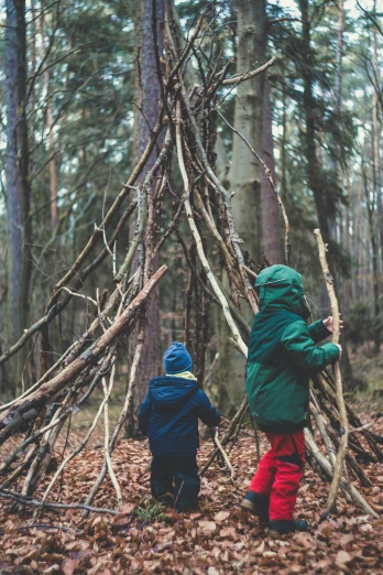two young children play in the woods near a teepee