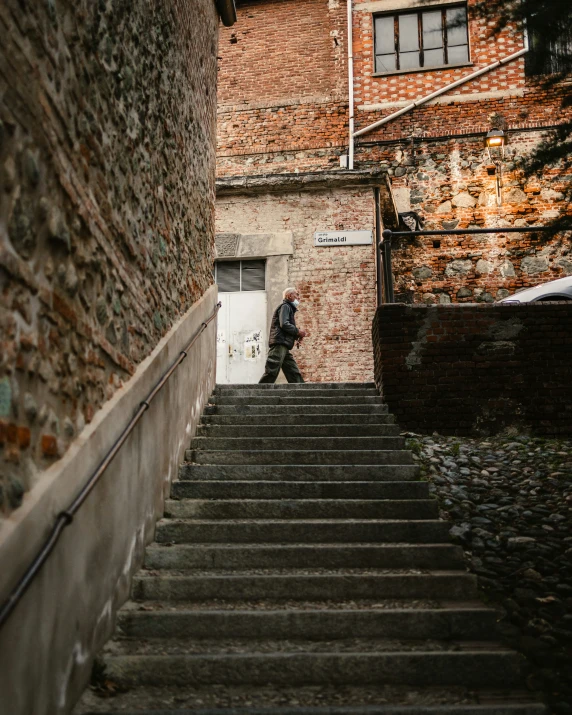 someone walking down the stairs in front of an old brick building