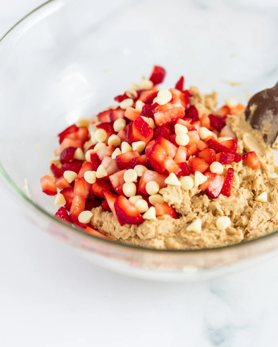 a bowl full of oatmeal and strawberries with a chocolate spoon