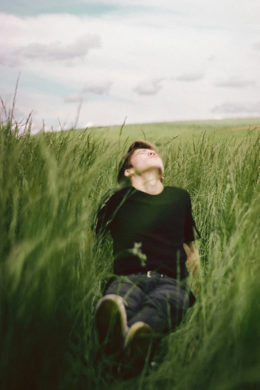 young man laying in the grass with his eyes closed