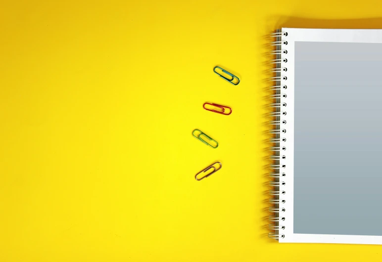 yellow background with various clips of paper, scissors, and pen