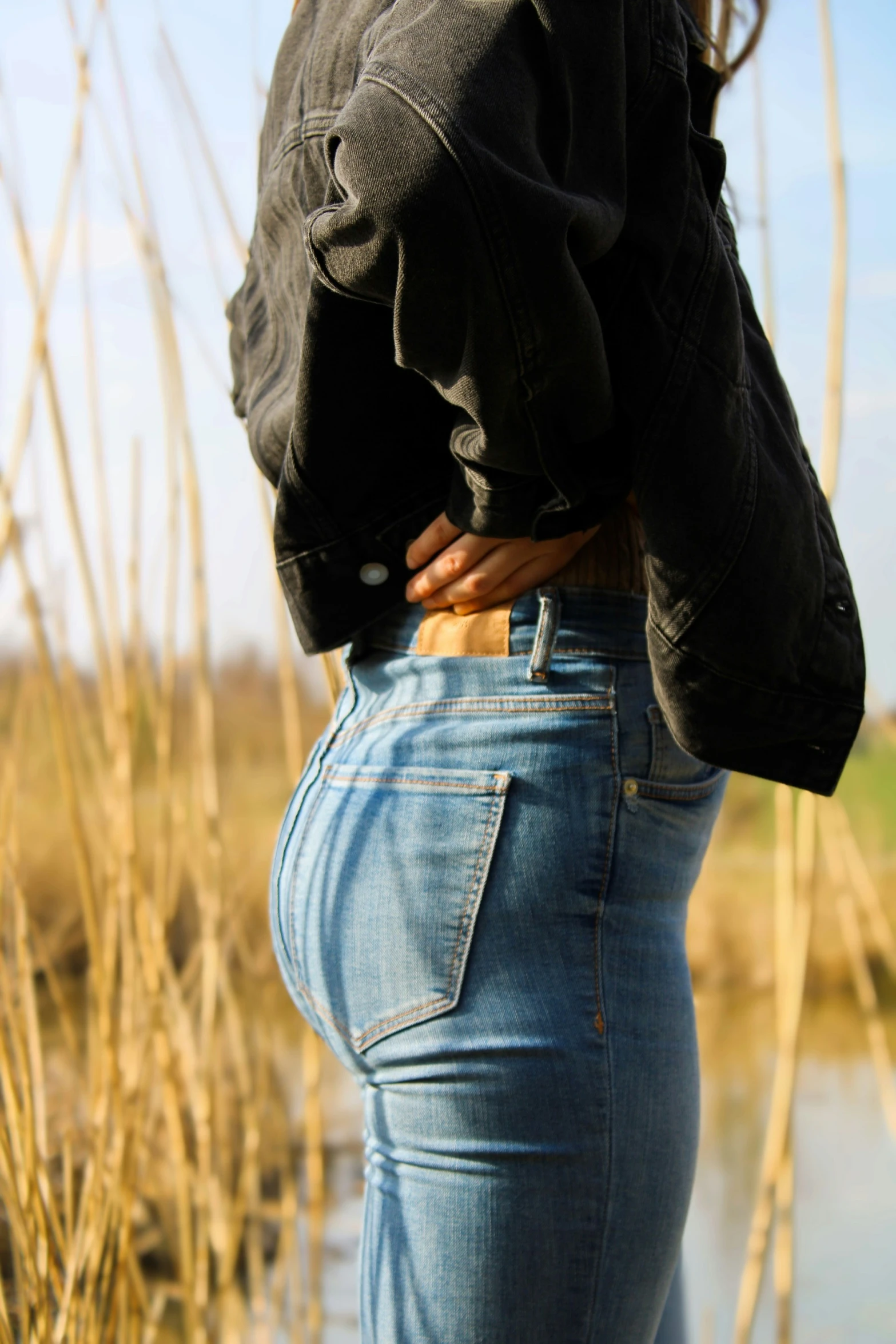 back view of woman standing near grass area in urban setting