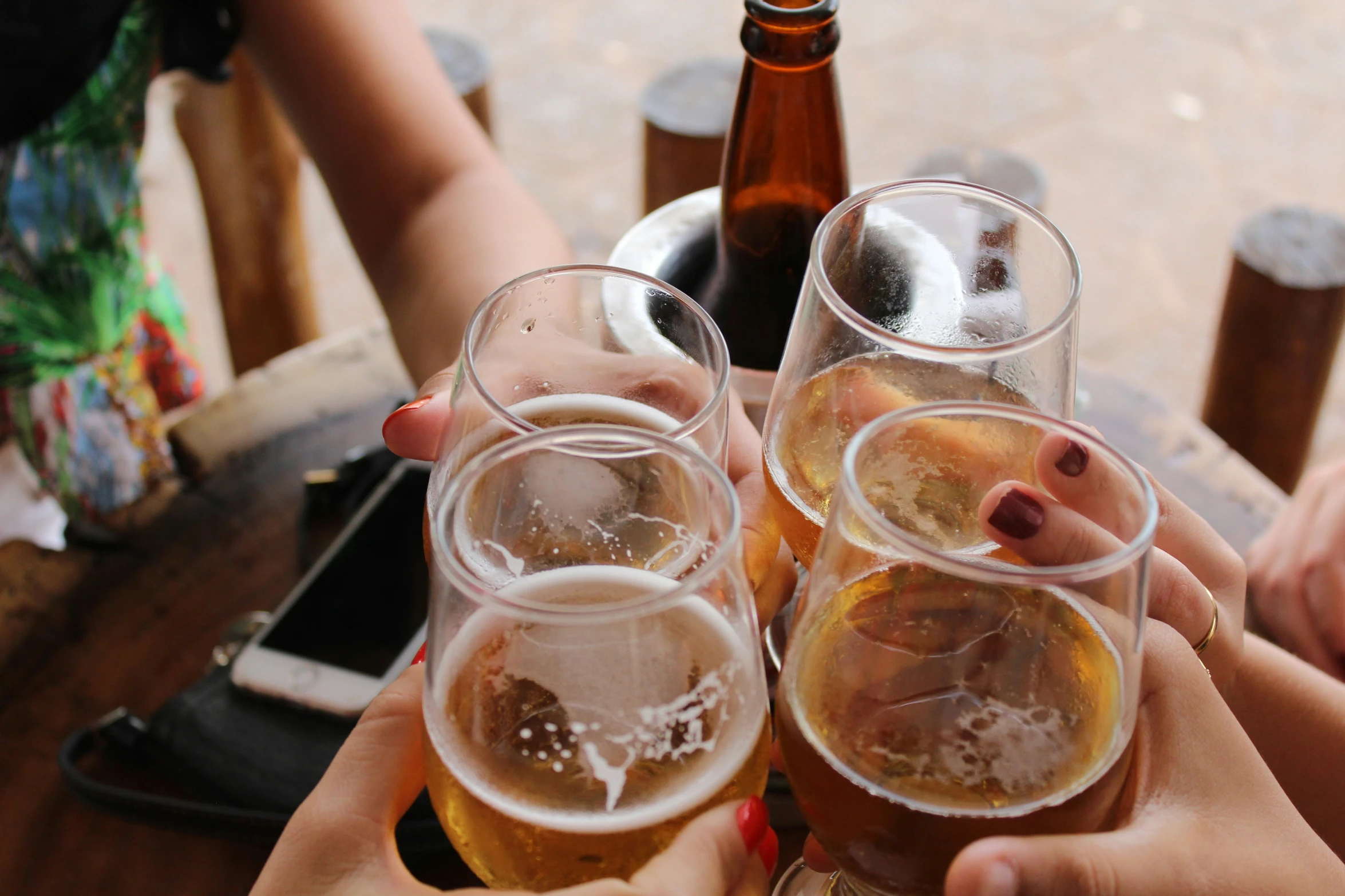 four people are toasting with beer from glasses