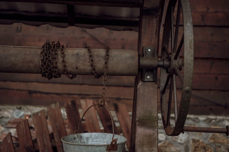 a bucket on a chain hanging from a wooden beam