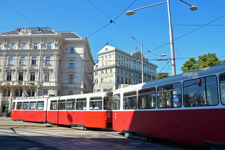 a red and white train on street in front of a large building