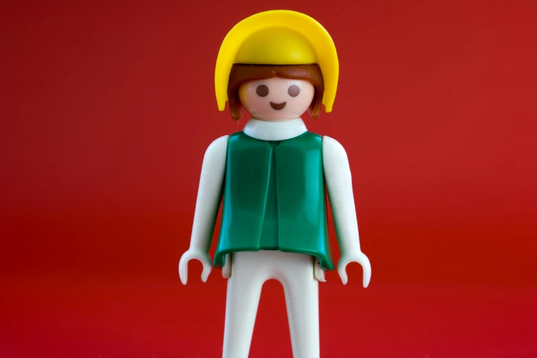 a toy figure wearing green outfit and a yellow hardhat