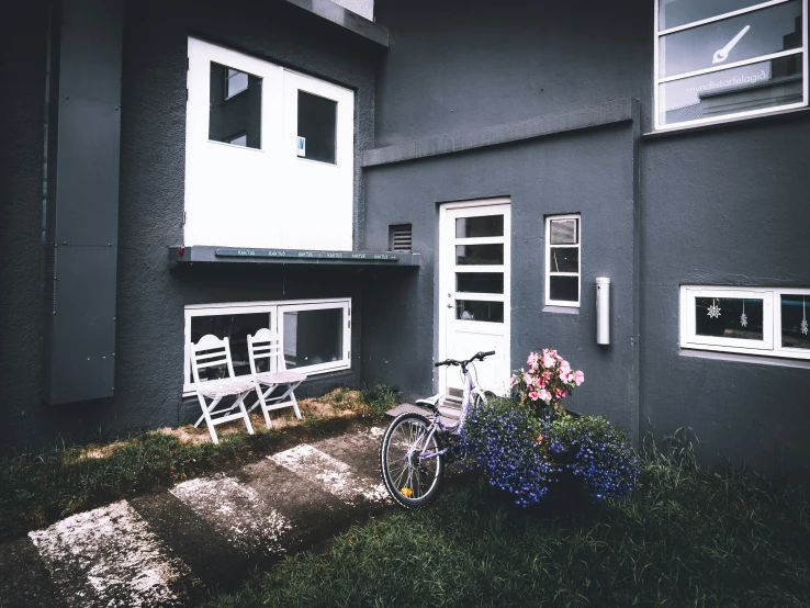 a gray house has a bike and flower