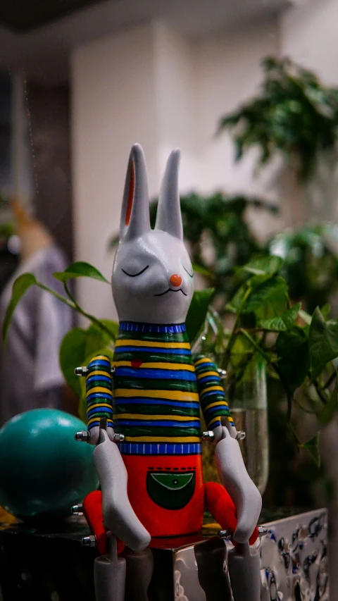 a plastic bunny sitting on a table next to potted plants