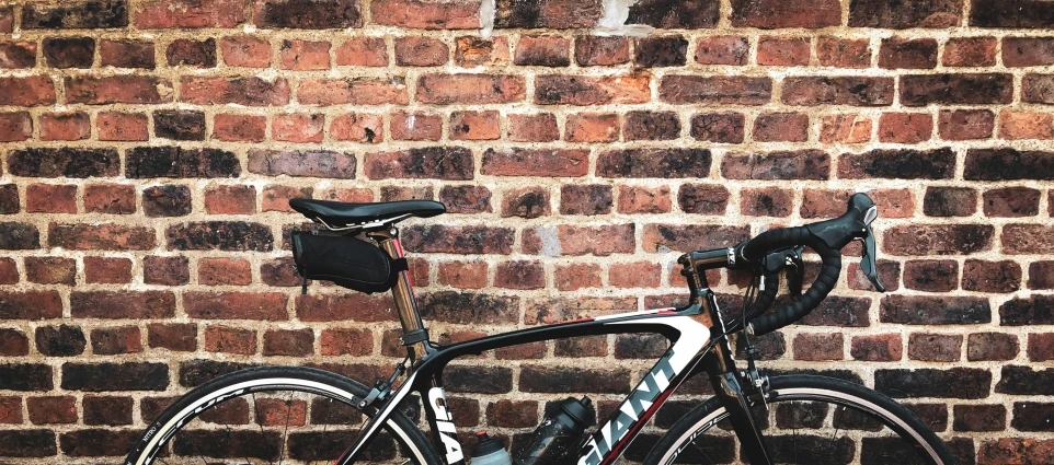 a black and white bike in front of a brick wall