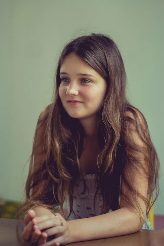 a smiling girl sitting down with her hands folded