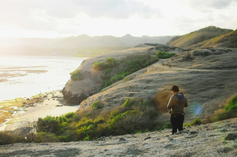 a person is standing on a mountain overlooking water and rocks