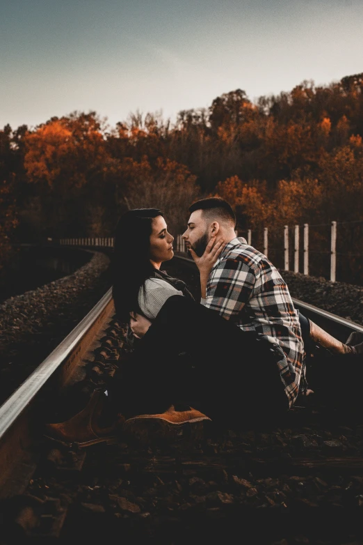 the man and woman are kissing on the train tracks