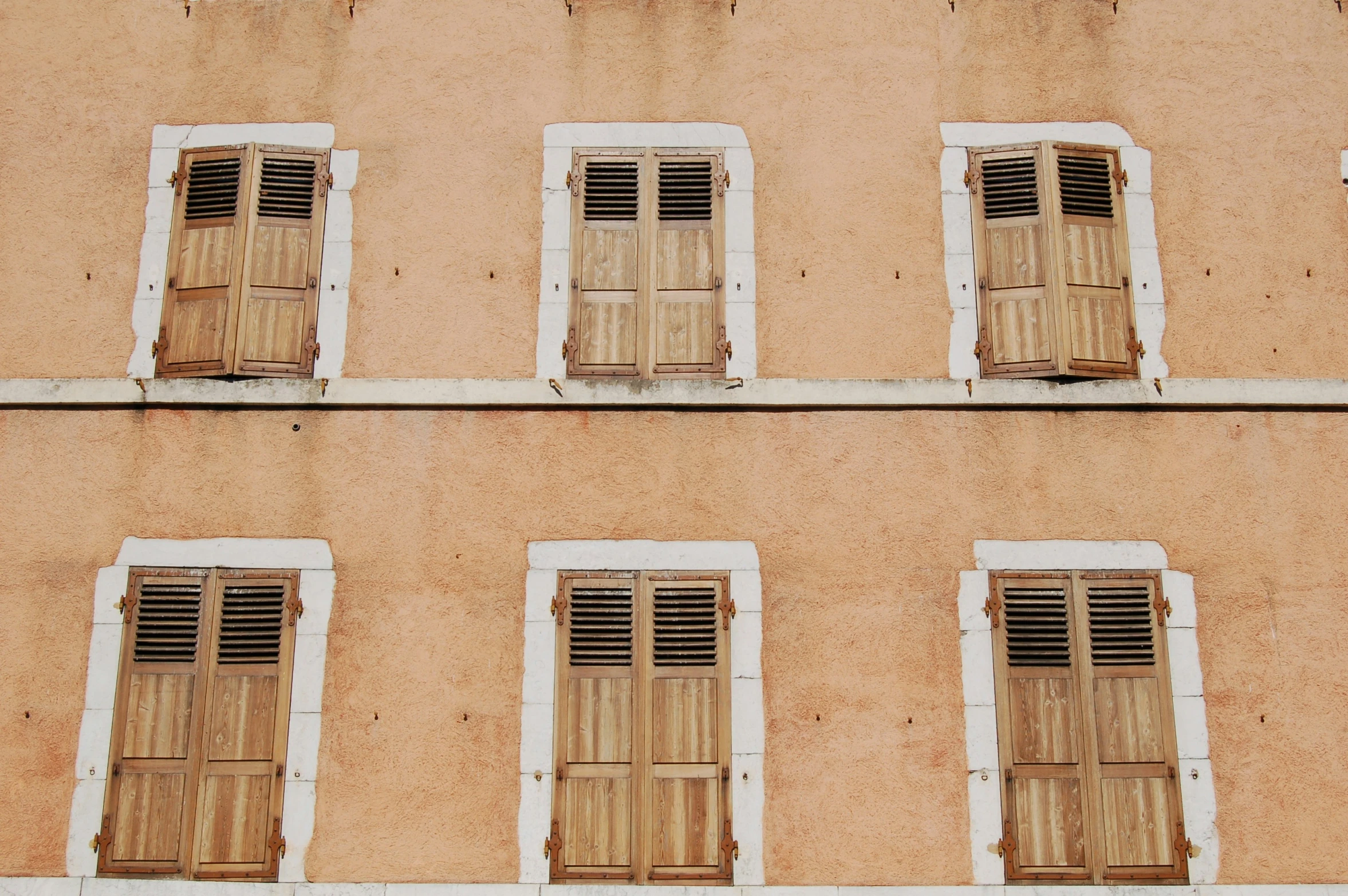 five windows in a tall building with multiple wooden shades