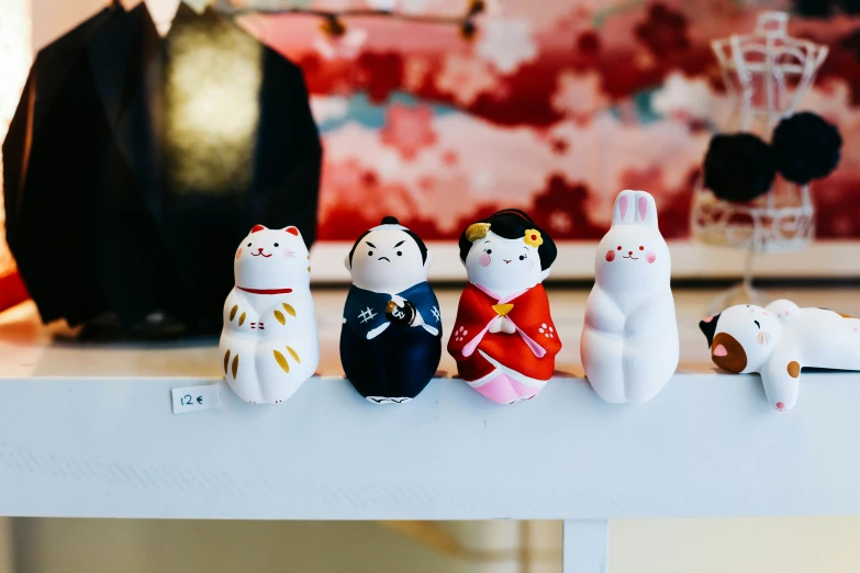 there are seven handmade dolls of asian characters on a shelf