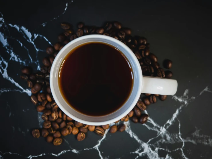 a white coffee cup on top of coffee beans