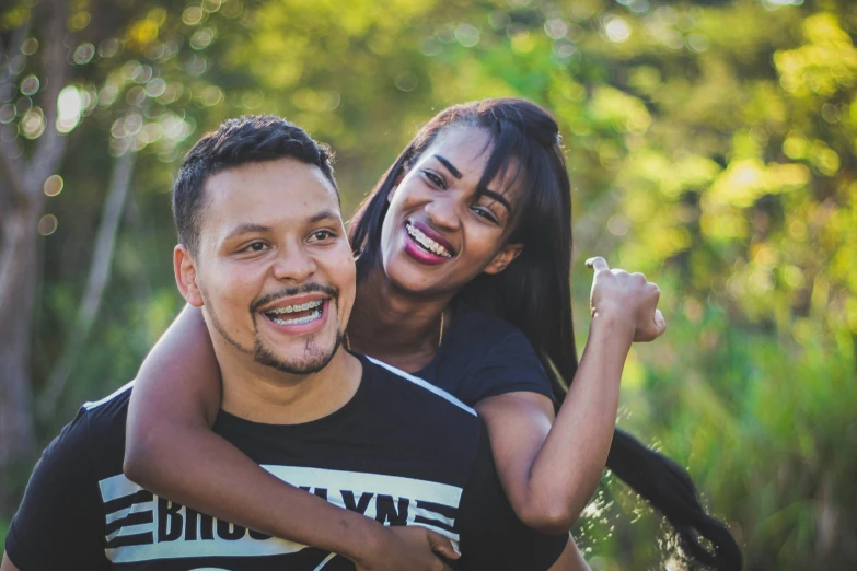 a young woman hugging a man that is standing in front of trees