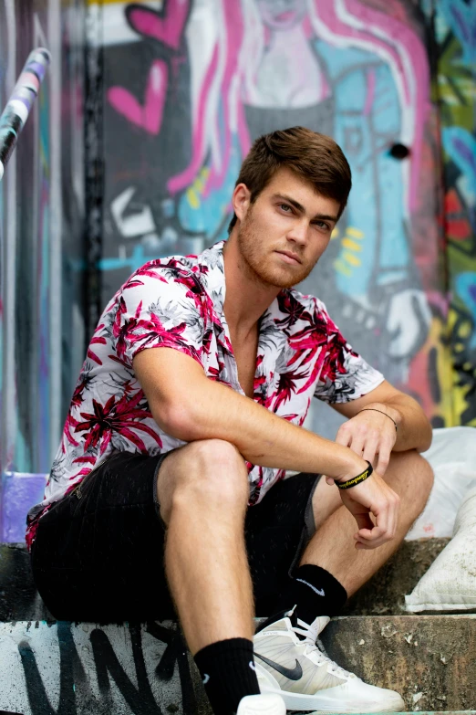 the skateboarder poses on his board in front of a colorful wall