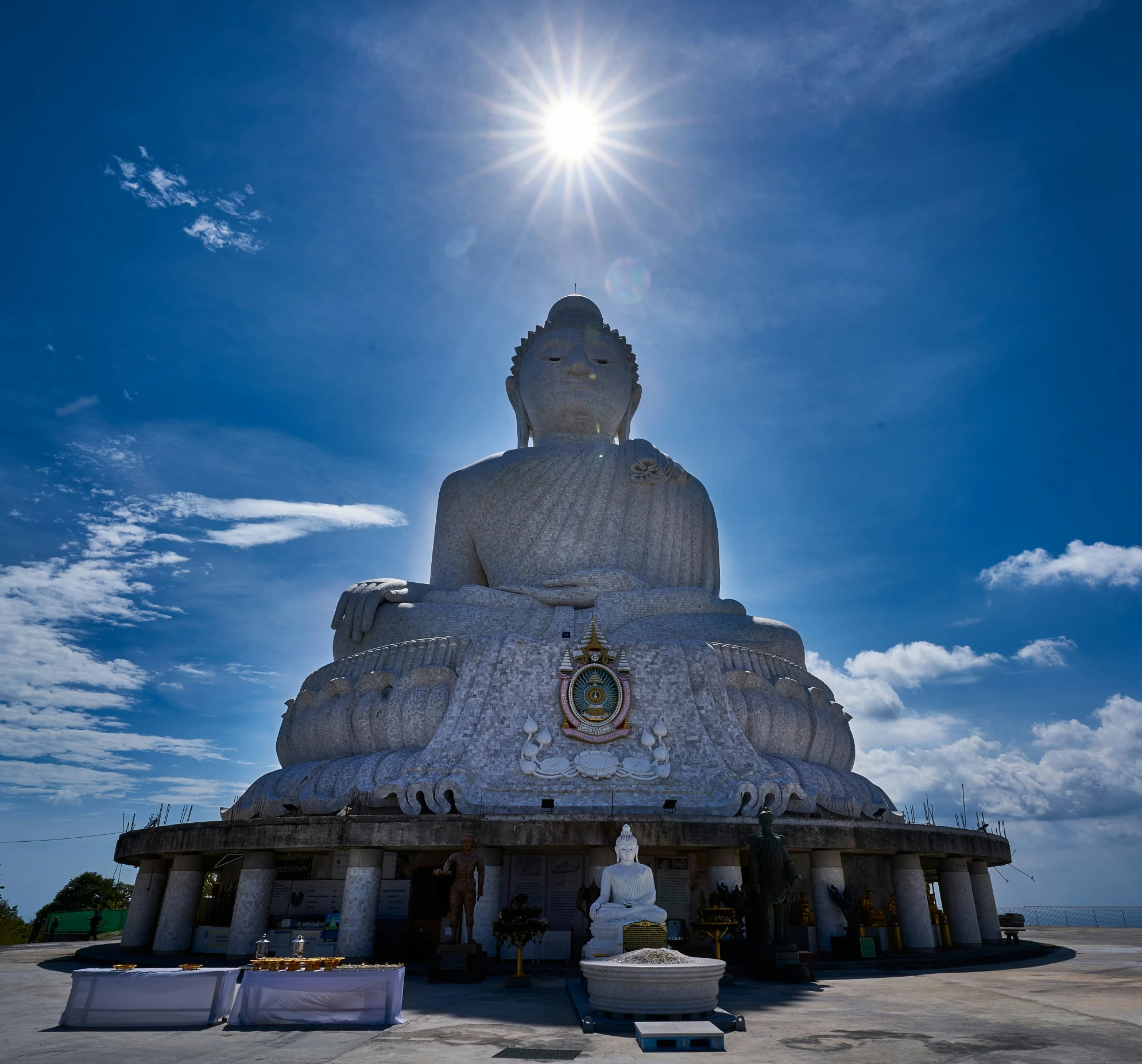 the sun is shining above a statue on top of the building