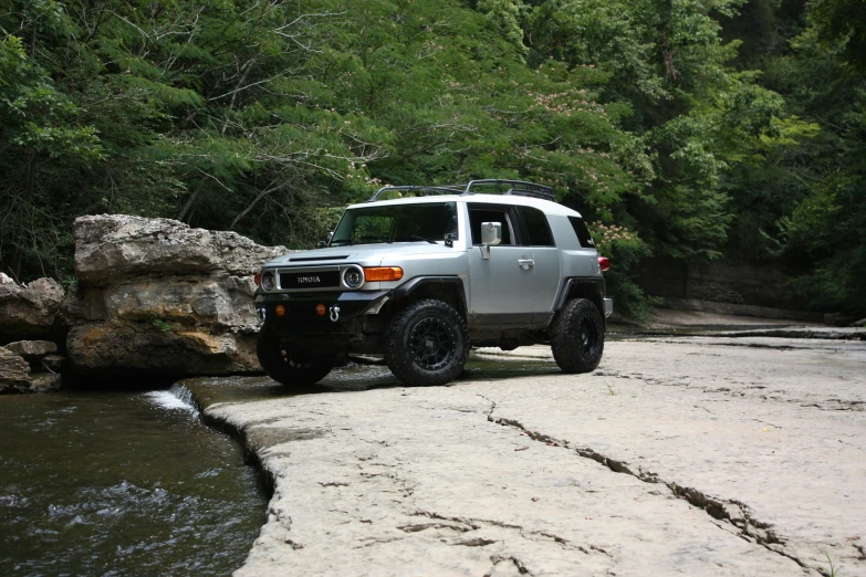 the truck is parked by a stream while rocks hold the water